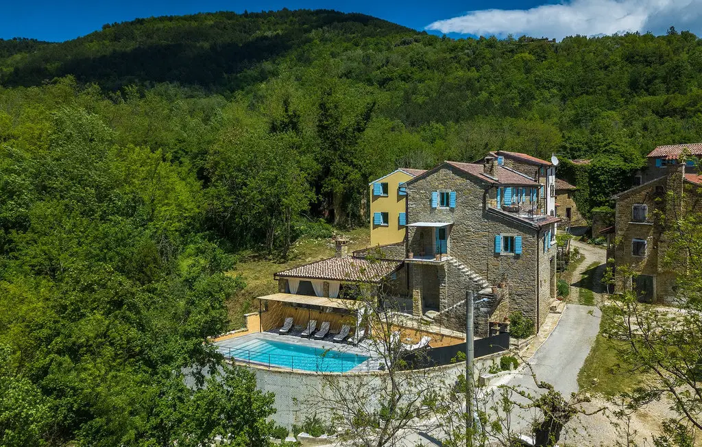 Rustic villa with pool amidst green hills.