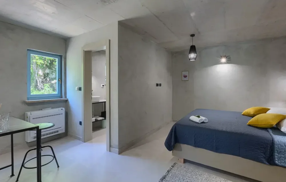 Modern bedroom with gray walls and blue bedding.