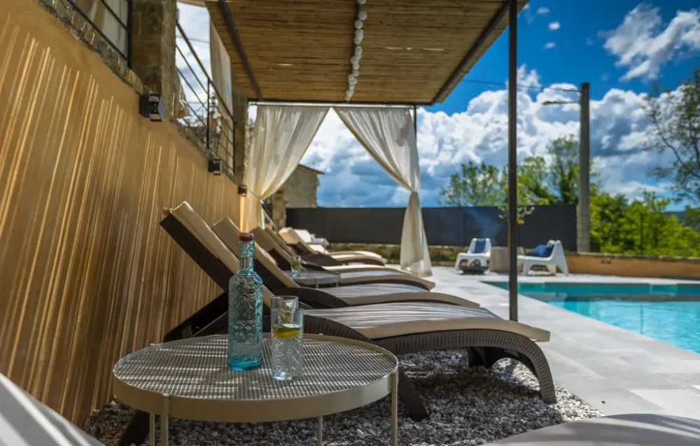 Poolside loungers with drinks and sunshade canopy.