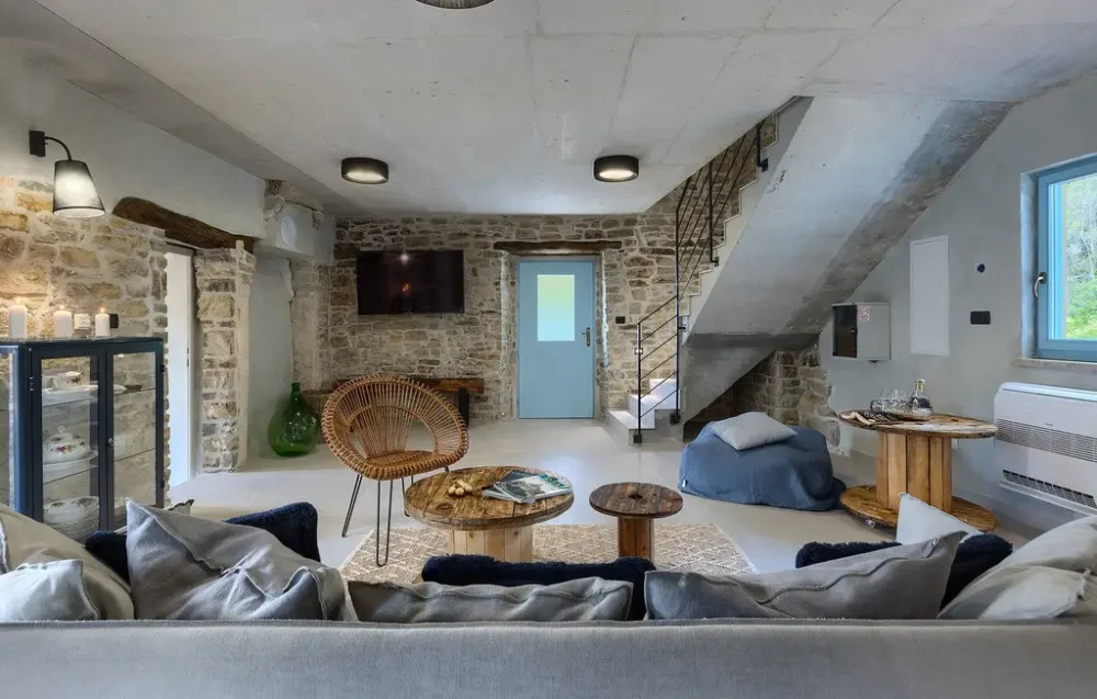 Modern rustic living room with stone walls and stairs.