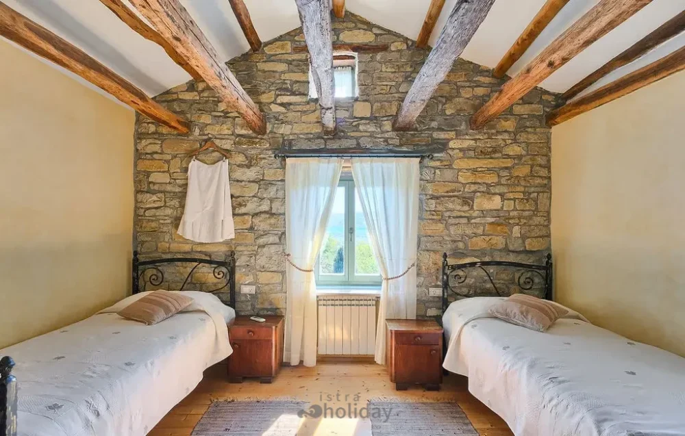 Rustic bedroom with twin beds and stone walls.