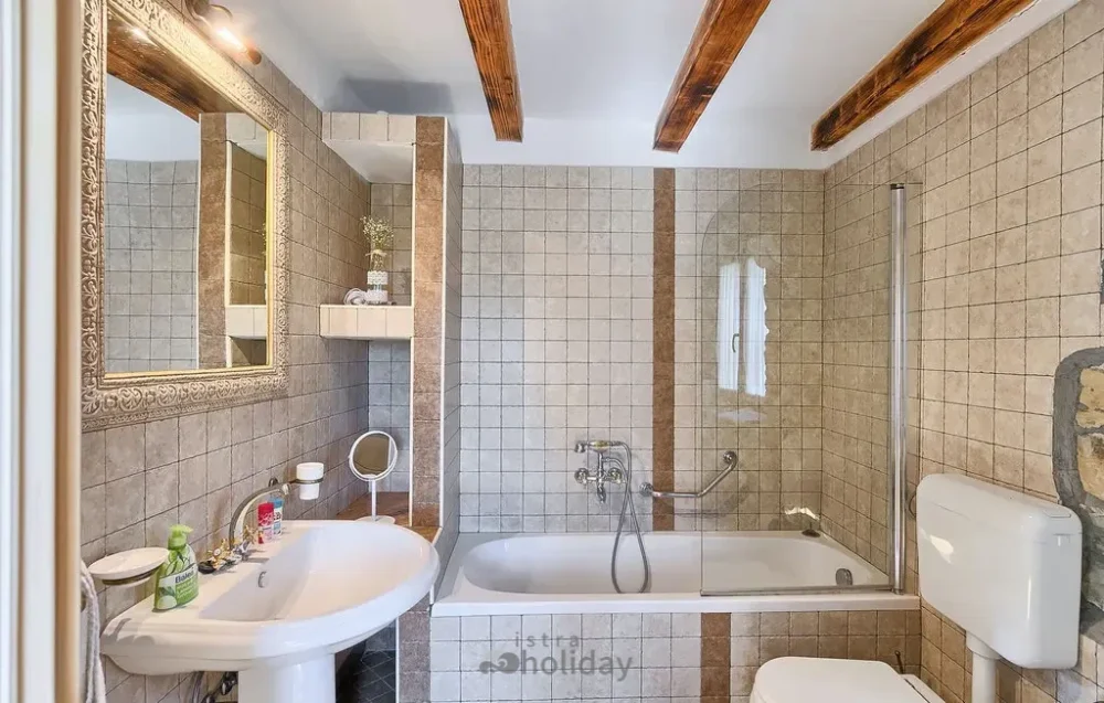 Rustic bathroom with bathtub and wood beam accents.