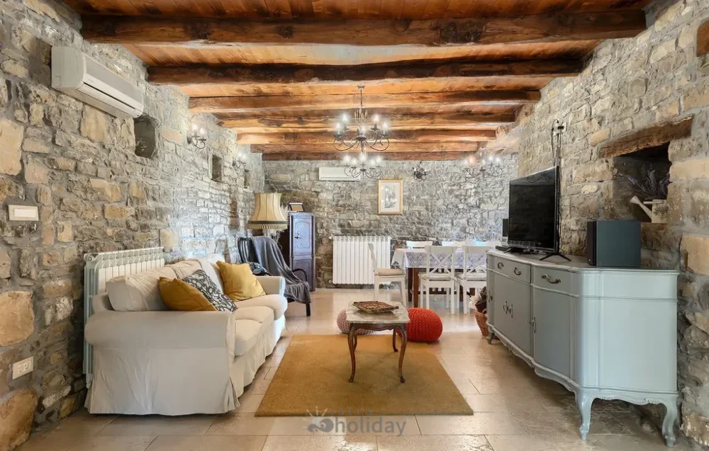 Rustic living room with stone walls and wooden beams.