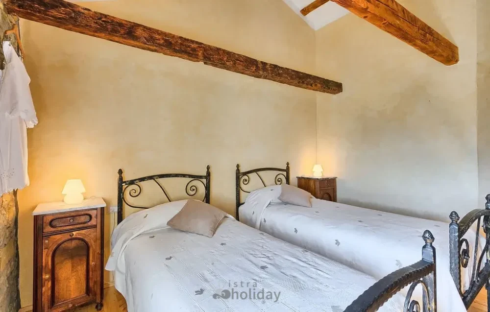 Rustic bedroom with twin beds and wooden beams.