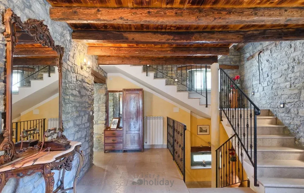 Rustic stone interior with wood beams and stairs.