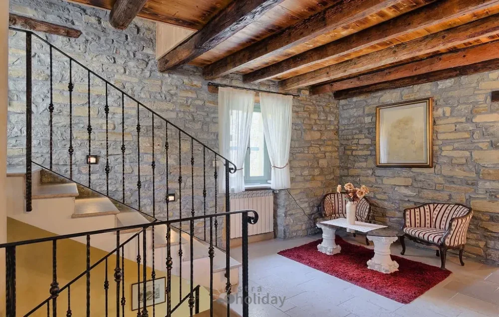 Cozy rustic stone living room with staircase.