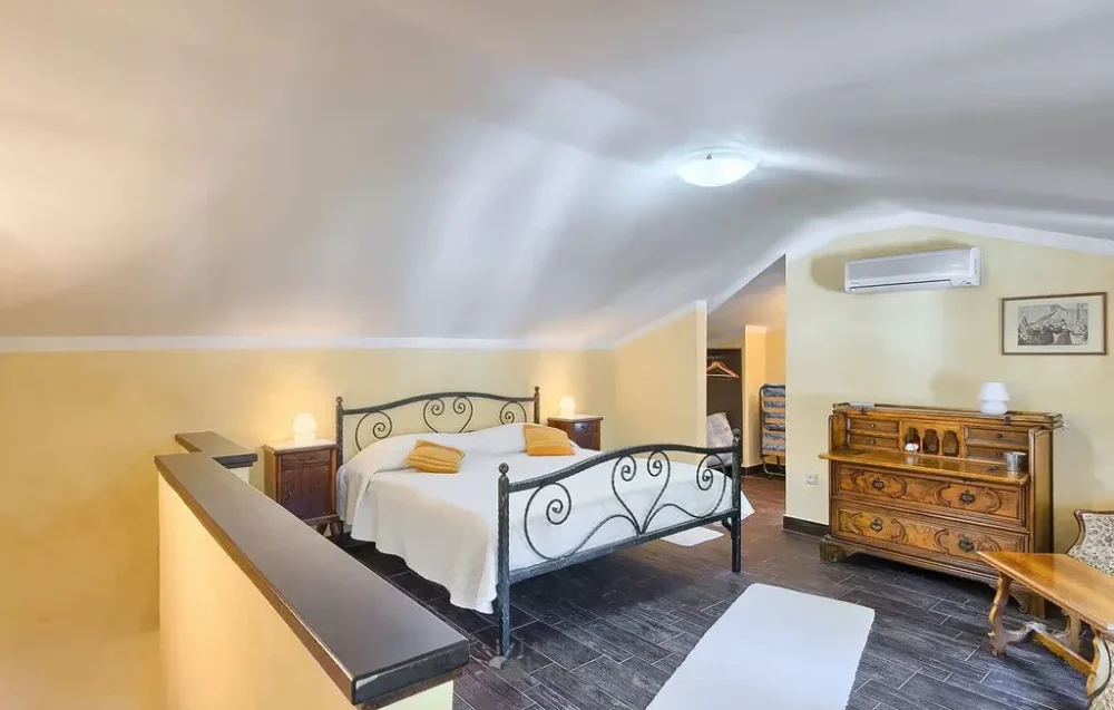 Elegant attic bedroom with double beds and wooden furniture.