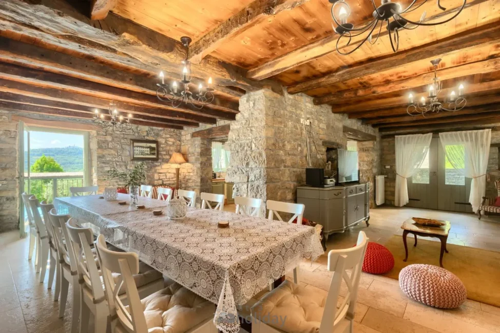 Rustic dining room with stone walls and wooden ceiling.