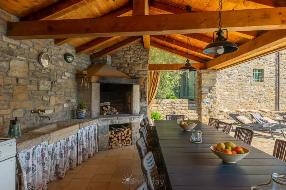 Outdoor stone kitchen and dining area with fireplace.