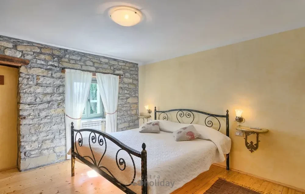 Cozy bedroom with stone walls and iron bed.