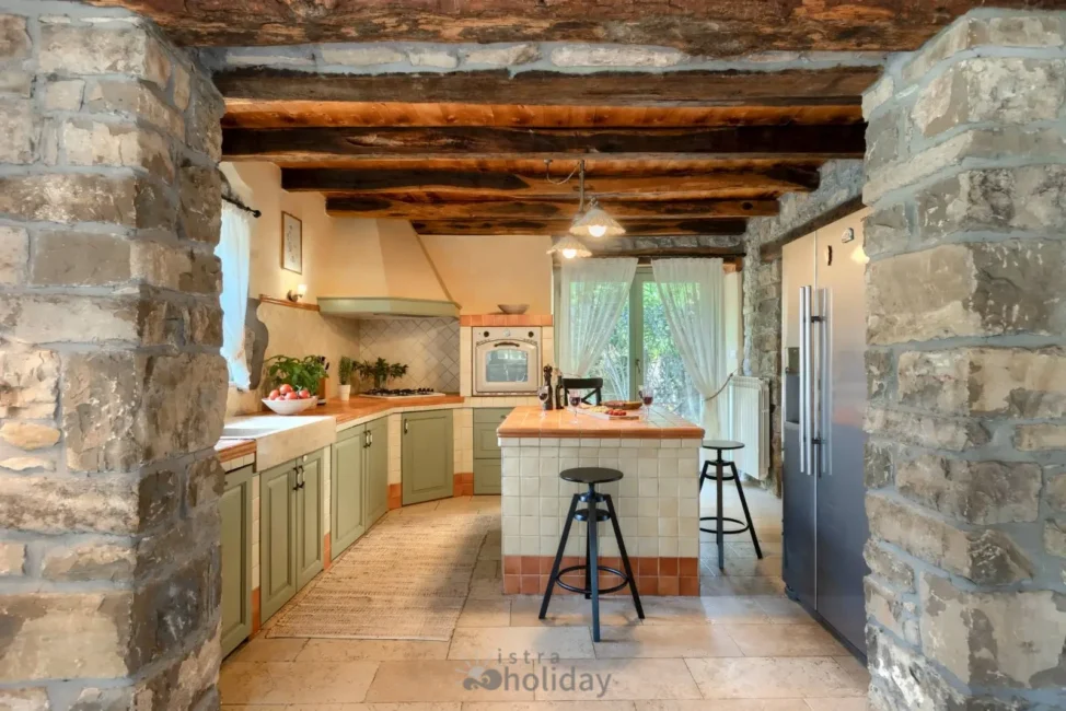 Rustic kitchen with stone walls and wooden beams.