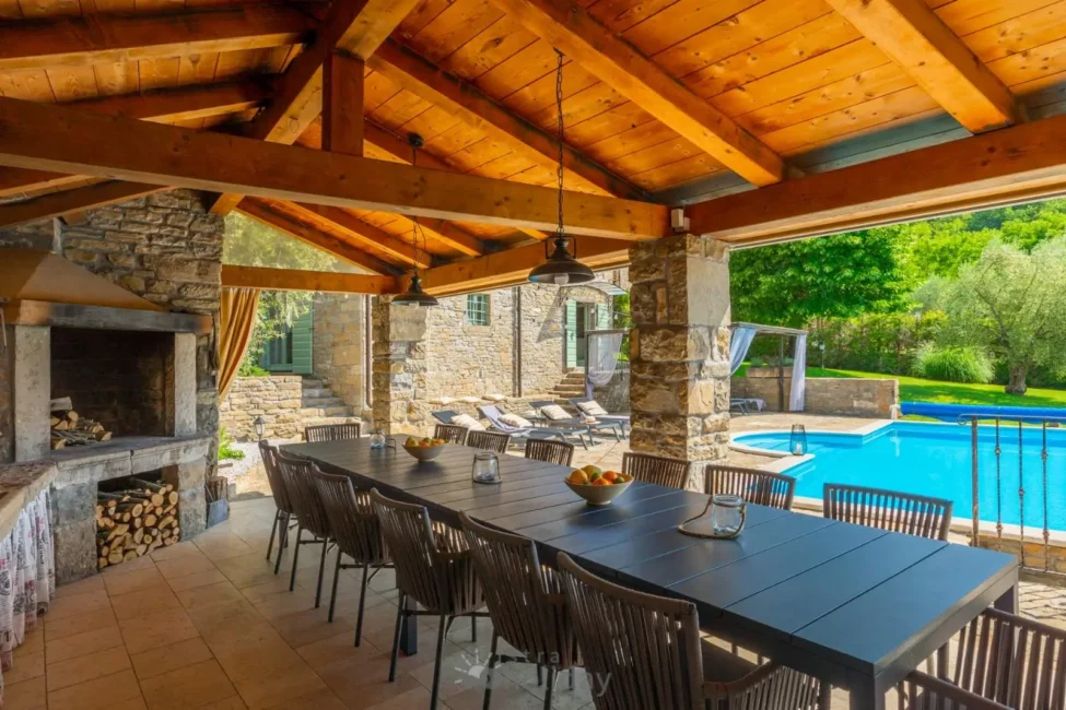 Covered patio with dining table near pool.