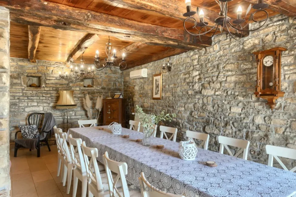 Rustic dining room with stone walls and wooden beams.