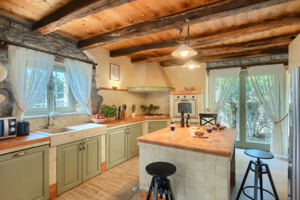 Rustic kitchen with wooden beams and stone walls.