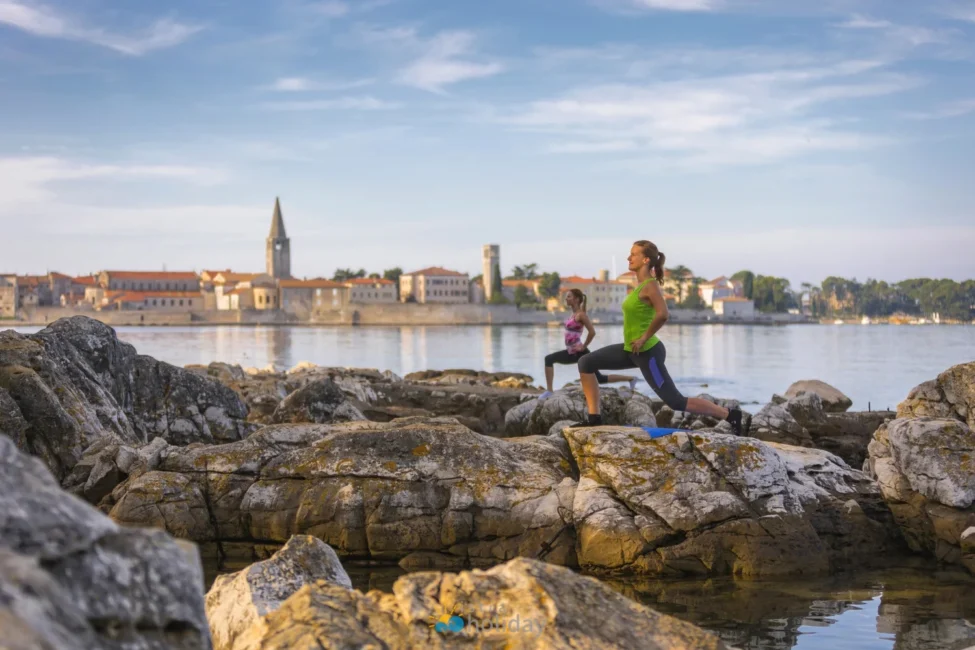 Two women exercising on rocky waterfront at sunrise