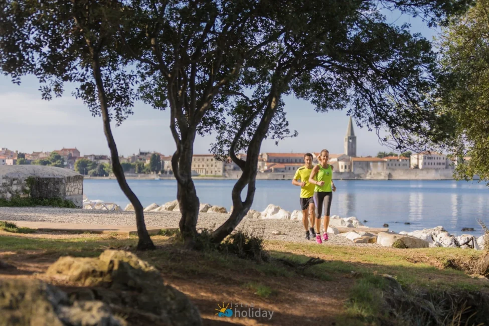 Couple jogging along waterfront with historic town backdrop