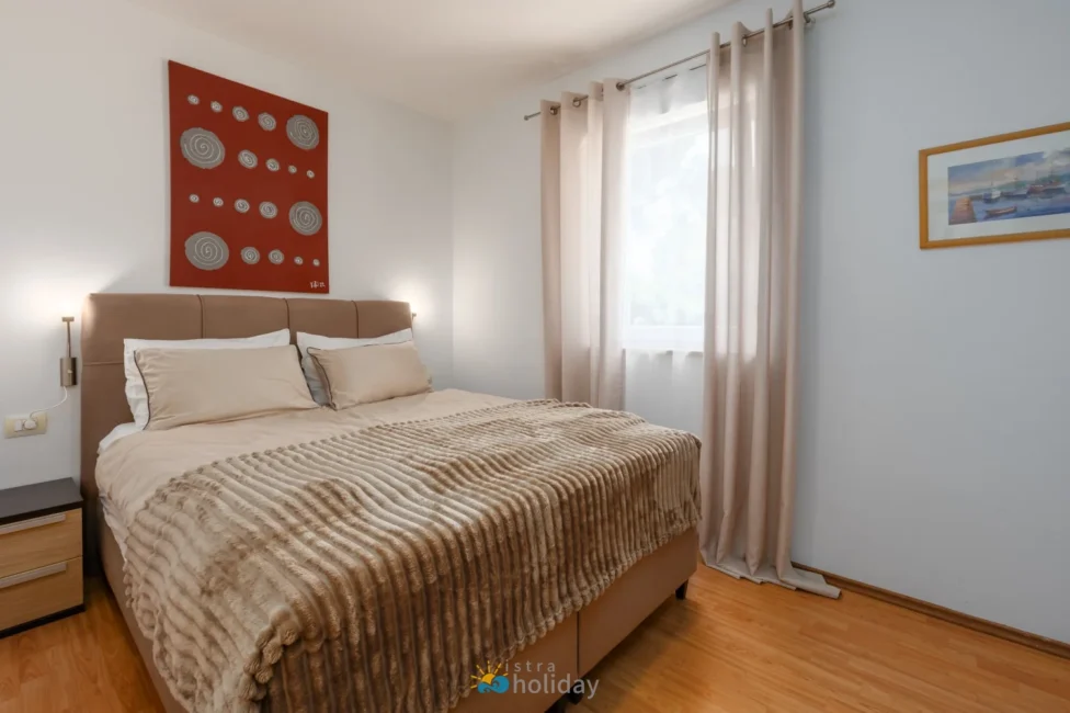 Cozy bedroom with beige bedding and red artwork