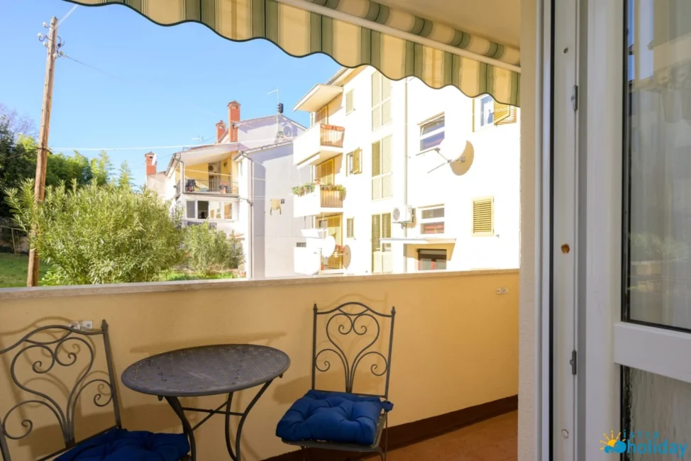 Balcony view with table, chairs, and nearby buildings.