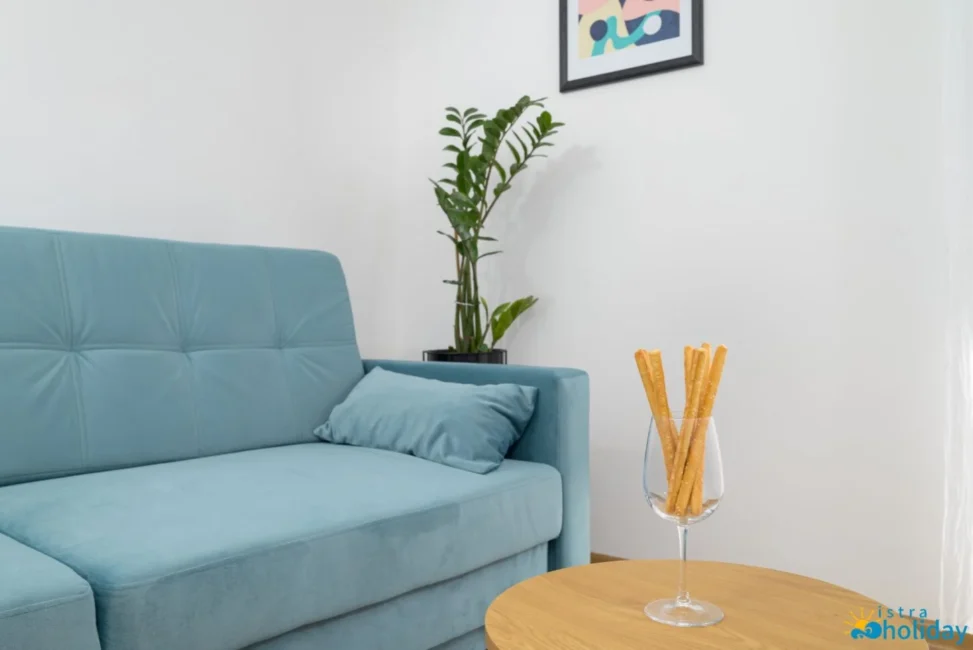 Modern living room with blue sofa, plant, breadsticks.