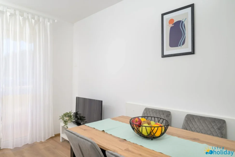 Modern dining area with fruit bowl and artwork.
