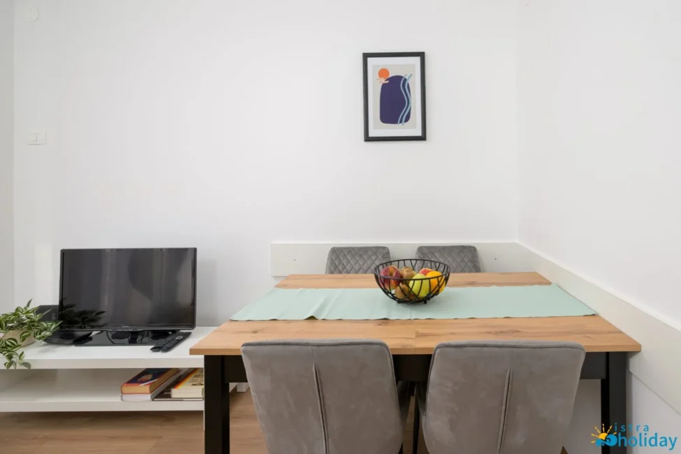 Dining area with TV and fruit bowl.