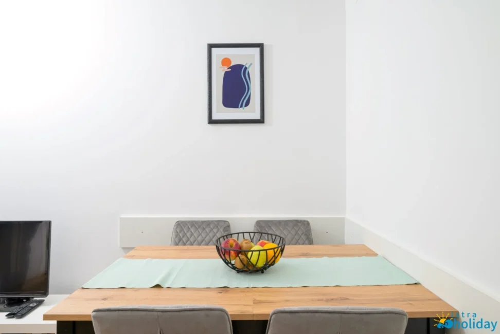 Dining table with fruit bowl and abstract art.