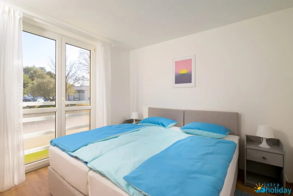 Bright bedroom with window and blue bedding.