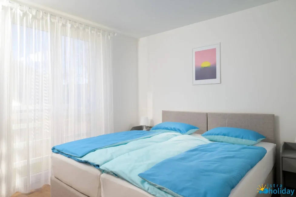 Modern bedroom with blue bedding and framed artwork.