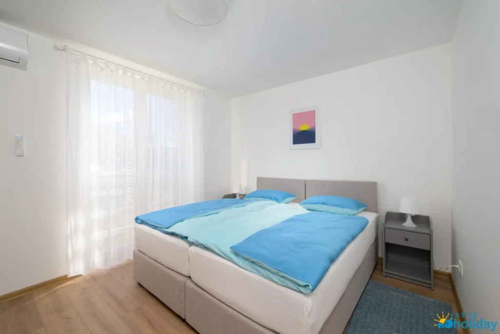 Bright modern bedroom with double bed and window.