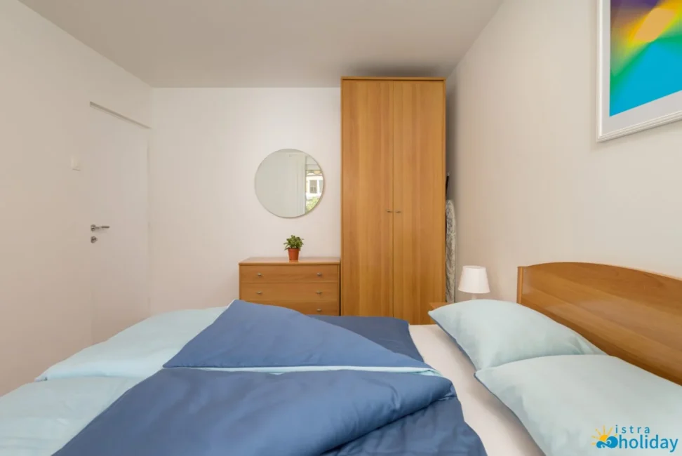 Cozy bedroom with blue bedding and wooden furniture.