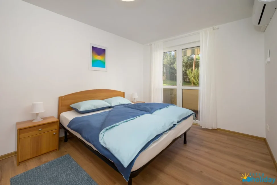 Cozy bedroom with bed, window view, and artwork.