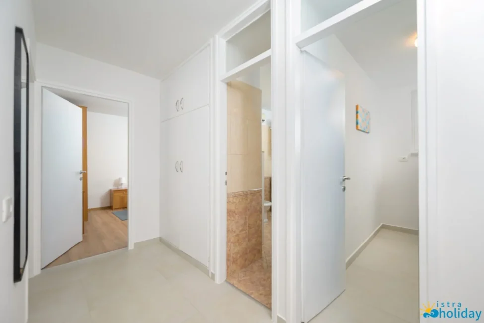 White hallway with doors to rooms and bathroom.
