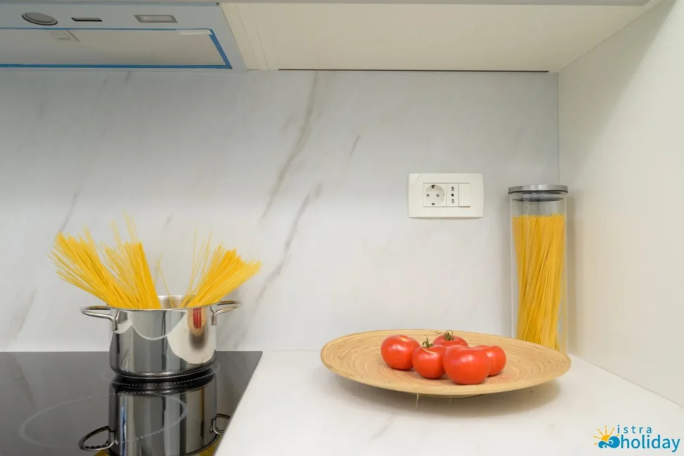 Spaghetti in pot, tomatoes on plate in kitchen