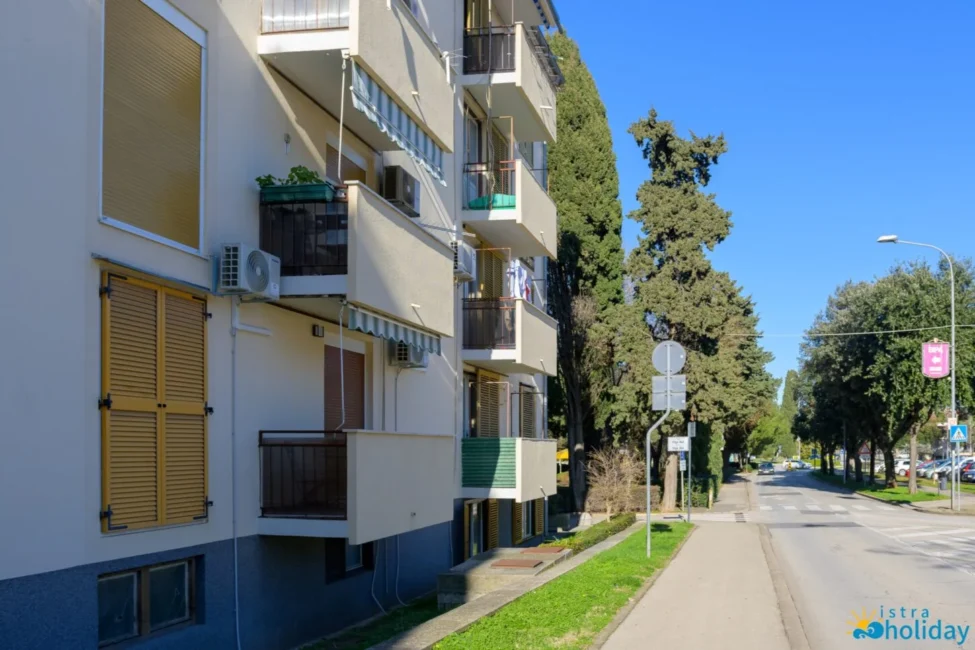 Sunny street with residential building and trees.