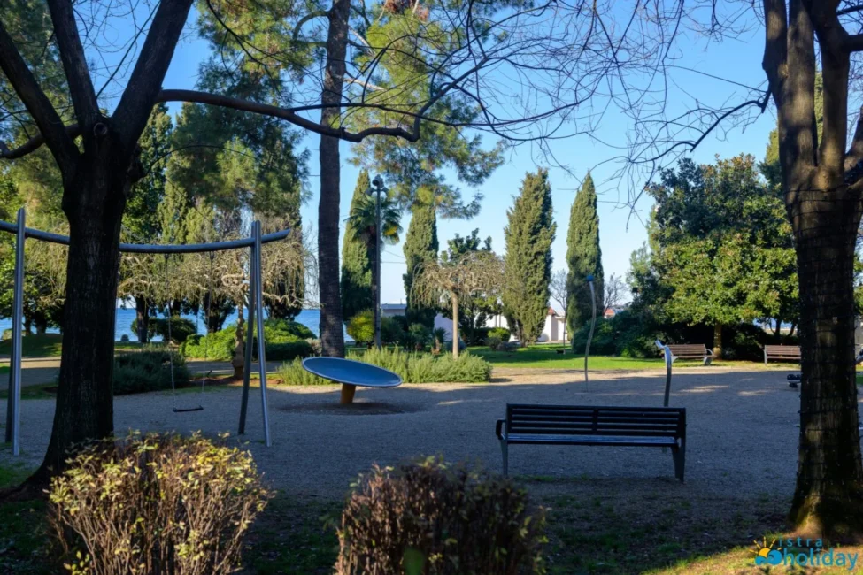 Scenic park with trees, benches, and playground equipment.