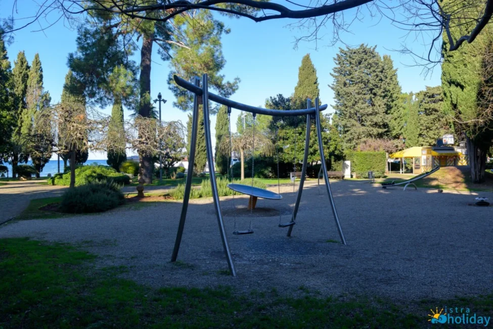 Playground swings in a scenic park setting.