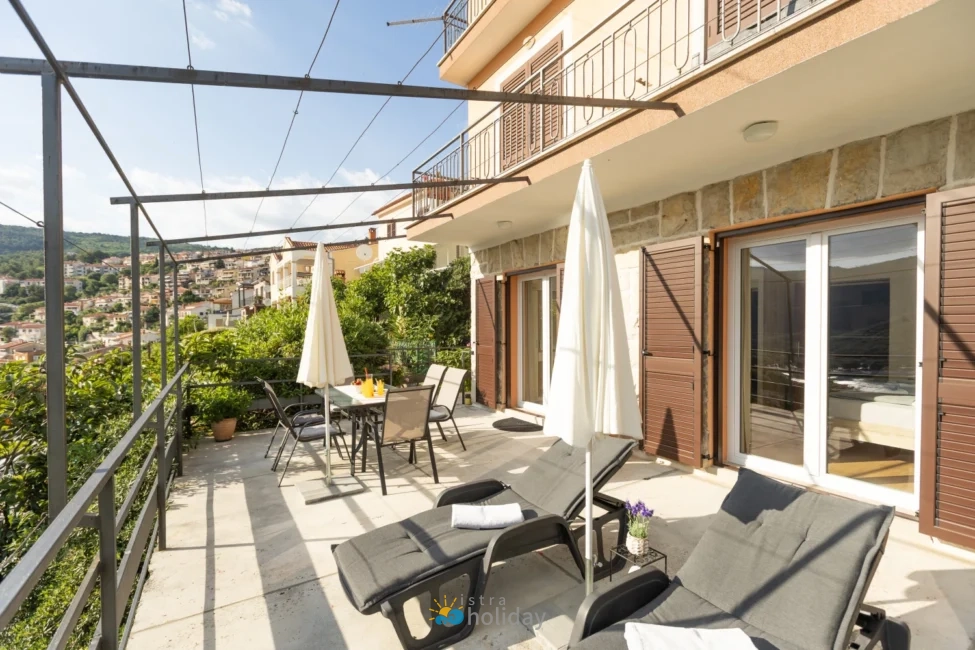 Sunny terrace with loungers overlooking hillside town