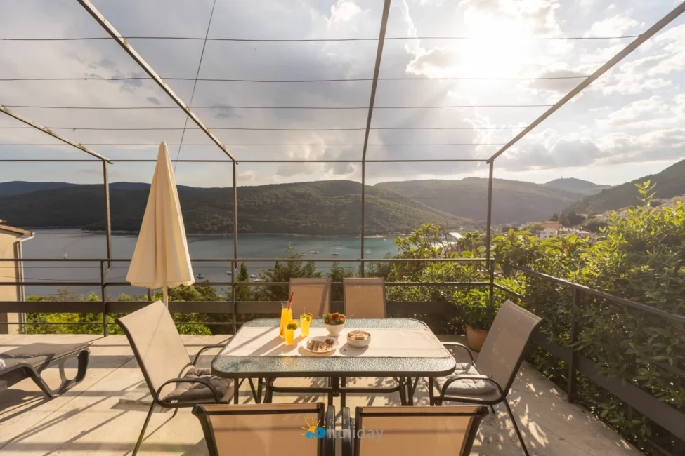 Terrace dining table overlooking scenic bay and hills