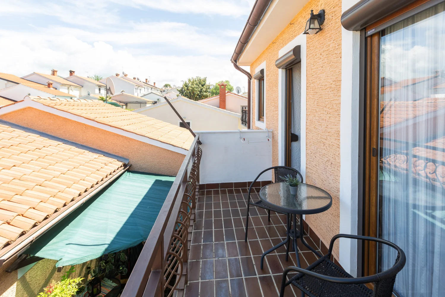 Small balcony with table overlooking tiled rooftops