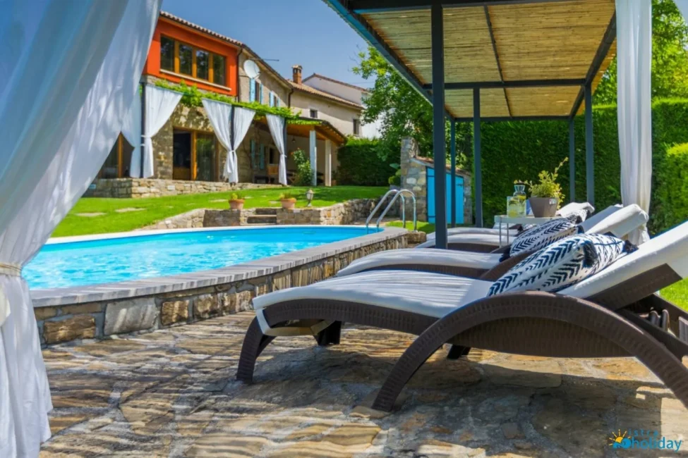 Luxury villa with pool and lounge chairs outdoors.