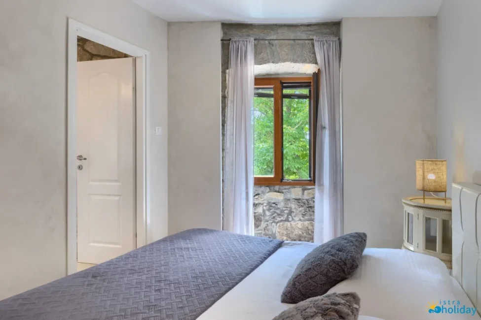 Cozy bedroom with stone window and curtain view.