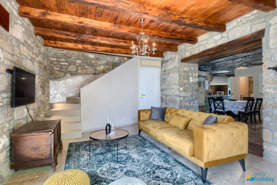 Rustic living room with stone walls and wooden ceiling.