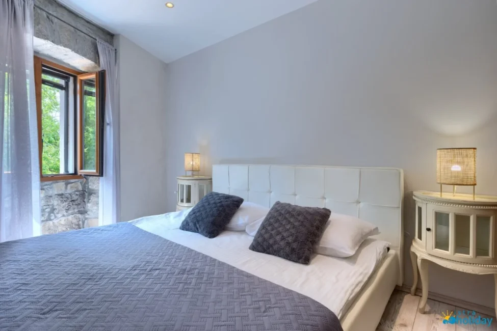 Cozy bedroom with large bed and open window view.