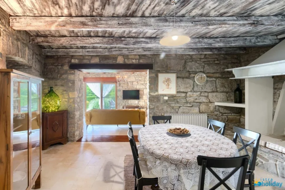 Rustic dining room with stone walls and wood ceiling.
