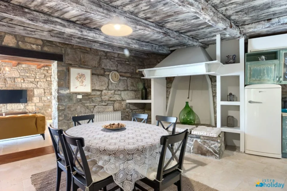Rustic kitchen with stone walls and wooden ceiling.