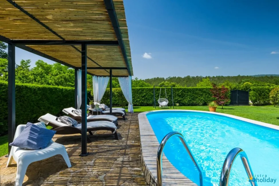 Outdoor pool with loungers and garden view.
