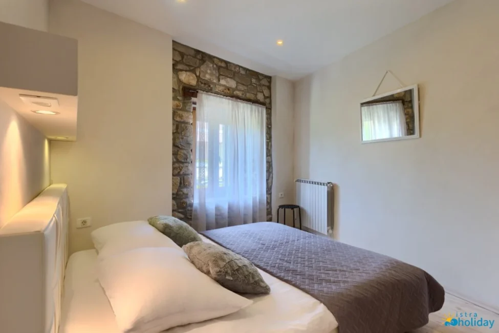 Cozy bedroom with stone wall and window view.
