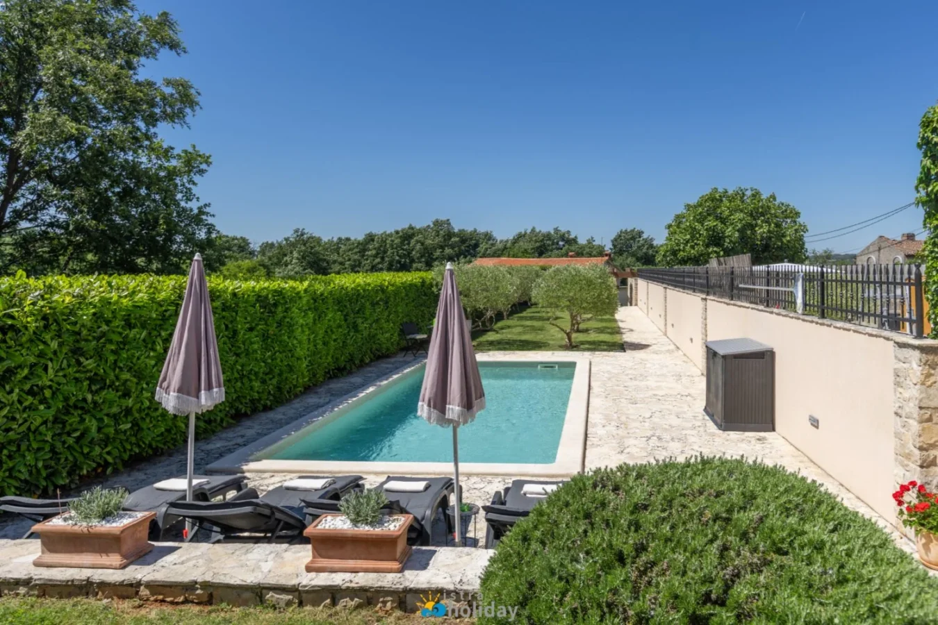 Private backyard pool with lounge chairs and umbrellas