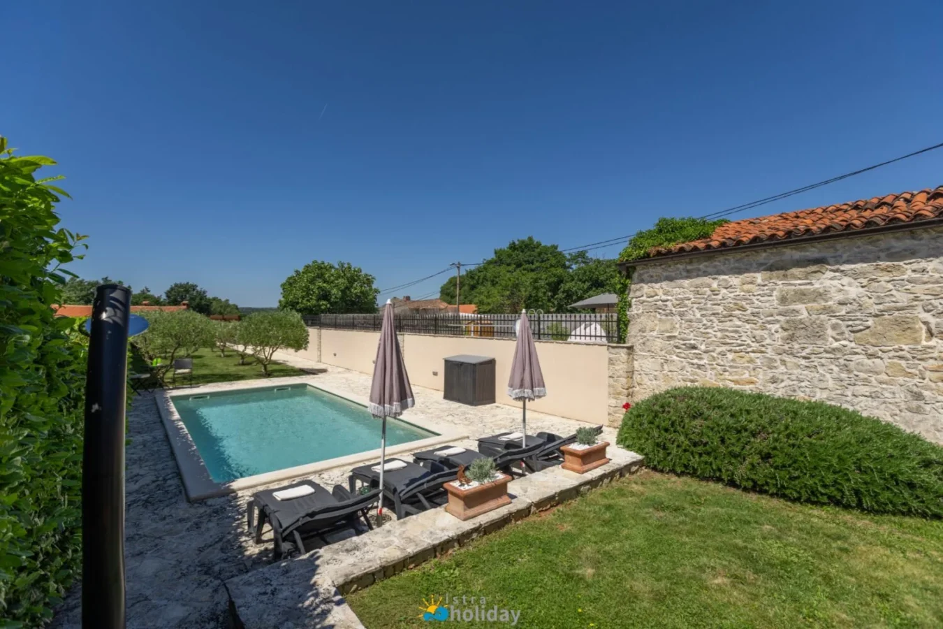 Private backyard pool with lounge chairs and umbrellas