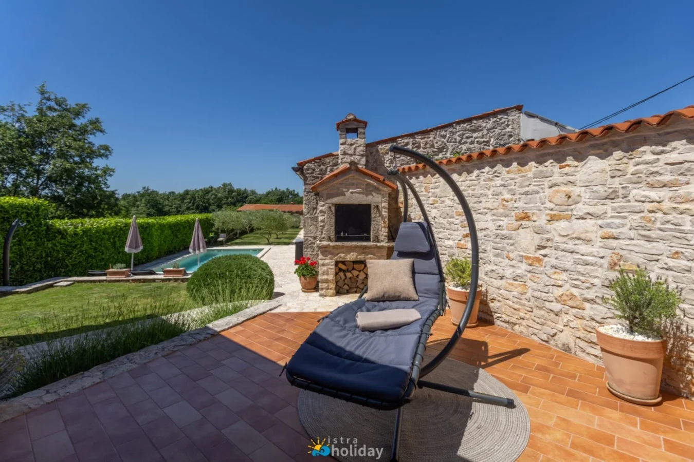 Stone patio with hanging chair and pool